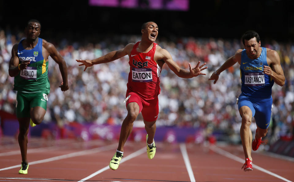 Ashton Eaton of the U.S. wins in the men's decathlon 100m heat next to Brazil's Luiz Alberto de Araujo (L) and Ukraine's Oleksiy Kasyanov (R) during the London 2012 Olympic Games at the Olympic Stadium August 8, 2012. REUTERS/Lucy Nicholson (BRITAIN - Tags: OLYMPICS SPORT ATHLETICS TPX IMAGES OF THE DAY) 