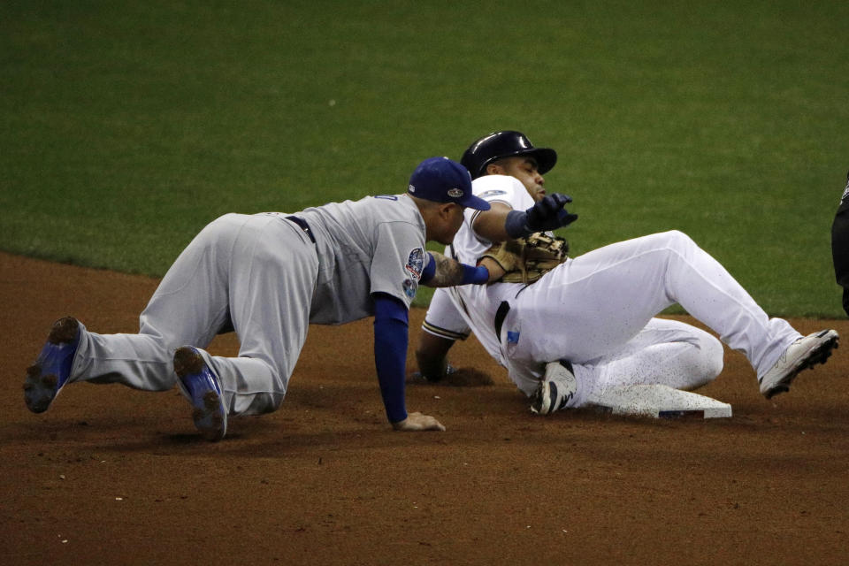 Los Angeles Dodgers shortstop Manny Machado misses a tag as Milwaukee Brewers' Jesus Aguilar slides safety into second during the seventh inning of Game 6 of the National League Championship Series baseball game Friday, Oct. 19, 2018, in Milwaukee. (AP Photo/Charlie Riedel)