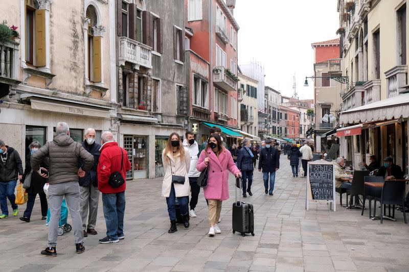 People wearing masks walk on a street, as the number of people infected by the coronavirus disease (COVID-19) continues to rise, in Venice