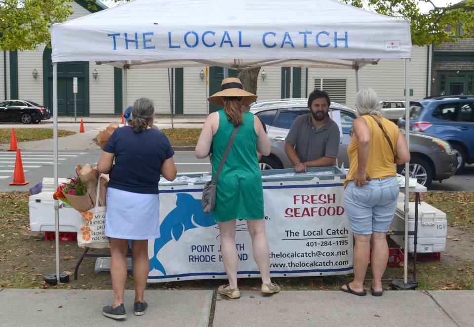 Dylan Hoy, general manager of seafood distributor The Local Catch, chats with customers at the Aquidneck Farmers Market on Memorial Boulevard in Newport.