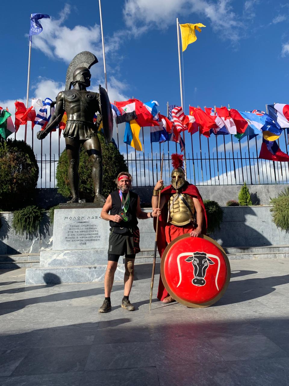 Mark Seeley standing next to a man dressed as a Trojan soldier as he completes the Tri-Fecta in Sparta, Greece.
