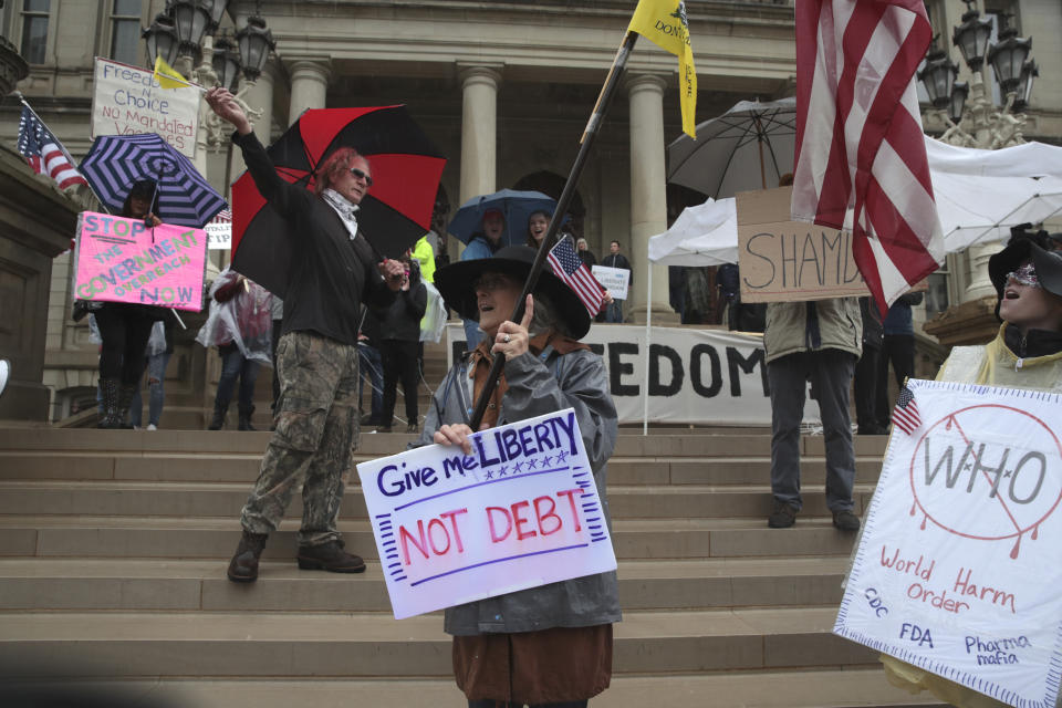 Protesters carry signs during a rally at the State Capitol in Lansing, Mich., Thursday, May 14, 2020. (AP Photo/Paul Sancya)