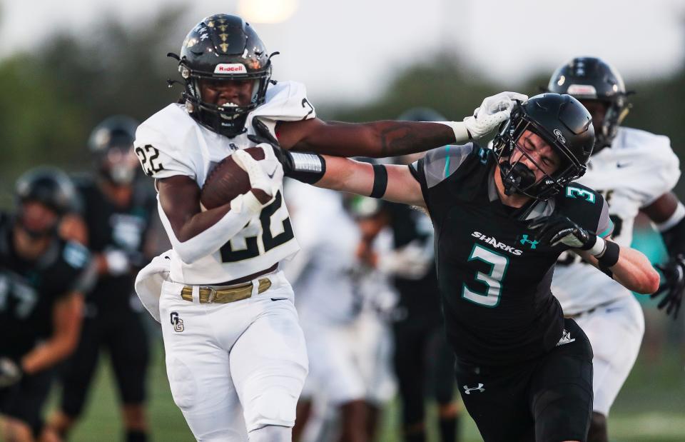 Golden Gate Titans running back Trayvon Jean (22) stiff arms Gulf Coast Sharks safety Cayden Daugherty (3) during the first quarter of a game at Gulf Coast High School in Naples on Friday, Sept. 22, 2023.