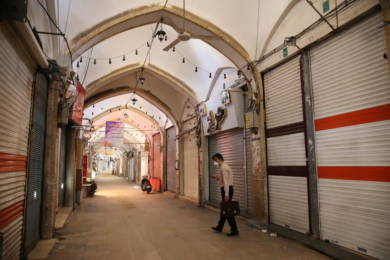 A man wearing a protective face mask, following the outbreak of coronavirus disease (COVID-19), walks next to closed shops in Qom