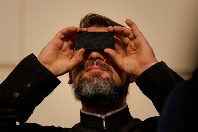 A priest looks through a welding filter during a partial solar eclipse in Bucharest, Romania, on Tuesday. People around the world gathered to witness the last solar eclipse of the year, a phenomenon where the moon briefly casts a black shadow that blocks the sun. It was visible across Europe, western Asia, northeastern Africa and the Middle East. (Photo: Andreea Alexandru via Associated Press)