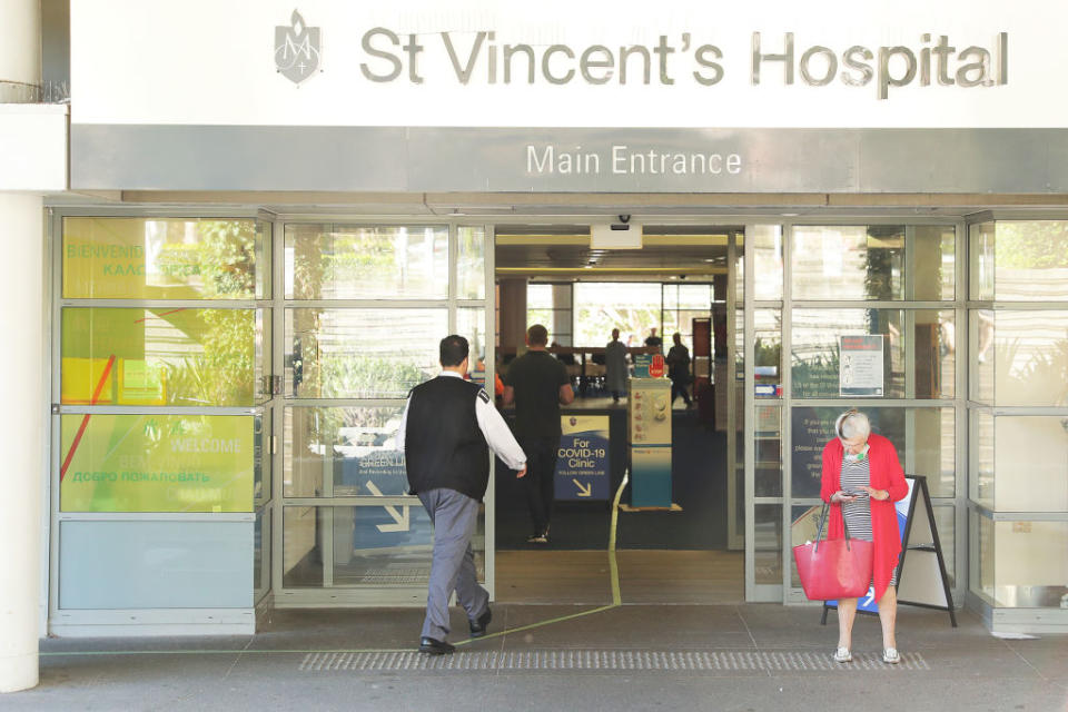 People pass signs for a COVID -19 Clinic at St Vincent's hospital in Sydney.