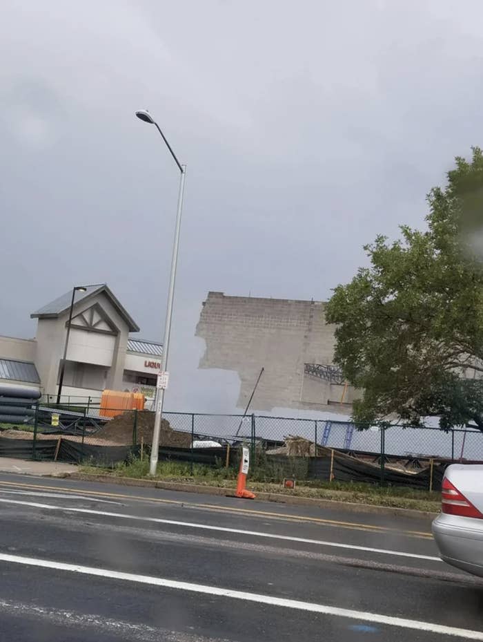 Someone is painting a building the same color as the current overcast sky, which makes the building seem like it's disappearing