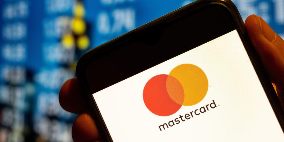 Hand holds a smartphone with the Mastercard logo on the screen