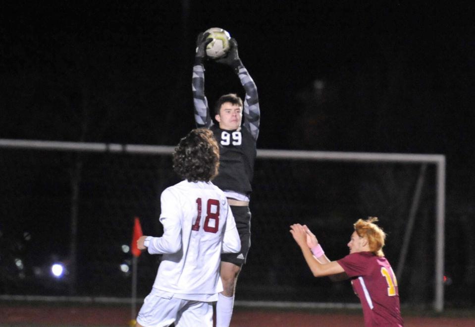 BC High goalkeeper Jake McConville leaps to make a save as Weymouth's Alex Pineiro, right, moves in during boys soccer Division 1 playoffs at Weymouth High School, Wednesday, Nov. 9, 2022.