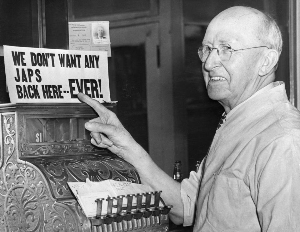 A barber points to his own anti-Japanese sign after Japanese-Americans were incarcerated during World War II. (Photo: Bettmann via Getty Images)