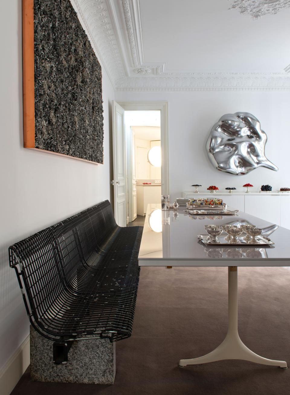 A long bench by Italian architect Osvaldo Borsani for Techno, which was designed for Malpensa Airport in Milan, helps anchor the dining room. The table is a George Nelson for Herman Miller piece. On the wall is a large work by artist Walead Beshty and Speech Bubble by German artist Jurgen Drescher.