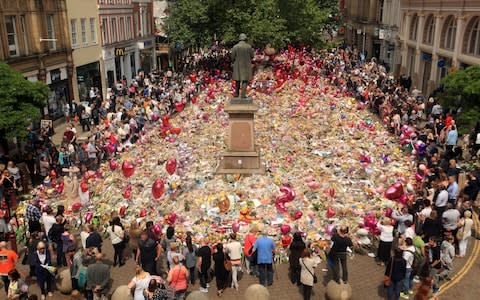 People look at flowers and tributes left in St Ann's Square in Manchester following the Manchester Arena terror attack - Credit: Danny Lawson/PA