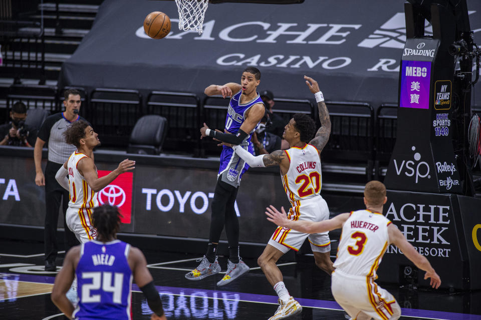 Sacramento Kings guard Tyrese Haliburton (0) throws a pass to guard Buddy Hield (24) as they are defended by Atlanta Hawks guard Trae Young (11), forward John Collins (20) and guard Kevin Huerter (3) during the first quarter of an NBA basketball game in Sacramento, Calif., Wednesday March 24, 2021. (AP Photo/Hector Amezcua)