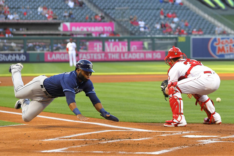 ADDS THAT MARGOT SCORES ON A FIELDING ERROR AND A SINGLE - Tampa Bay Rays' Manuel Margot, left, scores after a single by Brandon Lowe and a fielding error by Los Angeles Angels second baseman David Fletcher as catcher Max Stassi takes a late throw during the first inning of a baseball game Tuesday, May 4, 2021, in Anaheim, Calif. (AP Photo/Mark J. Terrill)