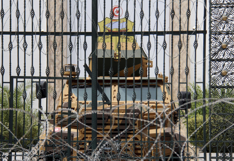 Barbed wire and a military armored personnel carrier block a side entrance of the Tunisian parliament in Tunis, Tuesday, July 27, 2021. The Ennahda party, has called for dialogue, following President Kais Saeid's sacking of the prime minister and suspension of parliament on Sunday. (AP Photo/Hassene Dridi)