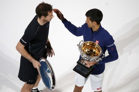 Serbia's Novak Djokovic (R) consoles Britain's Andy Murray while holding the men's singles trophy after winning their final match at the Australian Open tennis tournament at Melbourne Park, Australia, January 31, 2016. REUTERS/Jason Reed