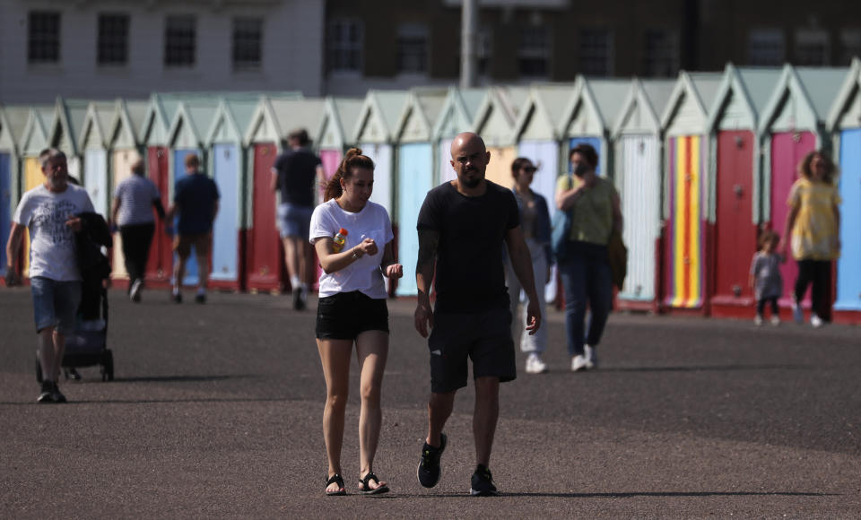 Strollers enjoy the sunny and warm weather whilst they keep their distance after the coronavirus outbreak and lockdown in Brighton, England, Saturday, April 11, 2020. in London, Saturday, April 11, 2020. The new coronavirus causes mild or moderate symptoms for most people, but for some, especially older adults and people with existing health problems, it can cause more severe illness or death.(AP Photo/Frank Augstein)