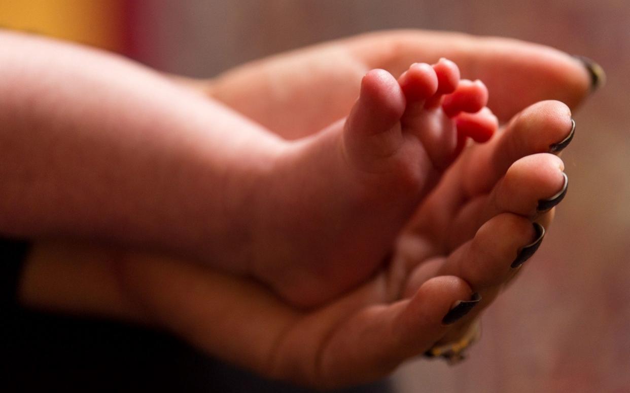 a mother holds the feet of a new baby - PA