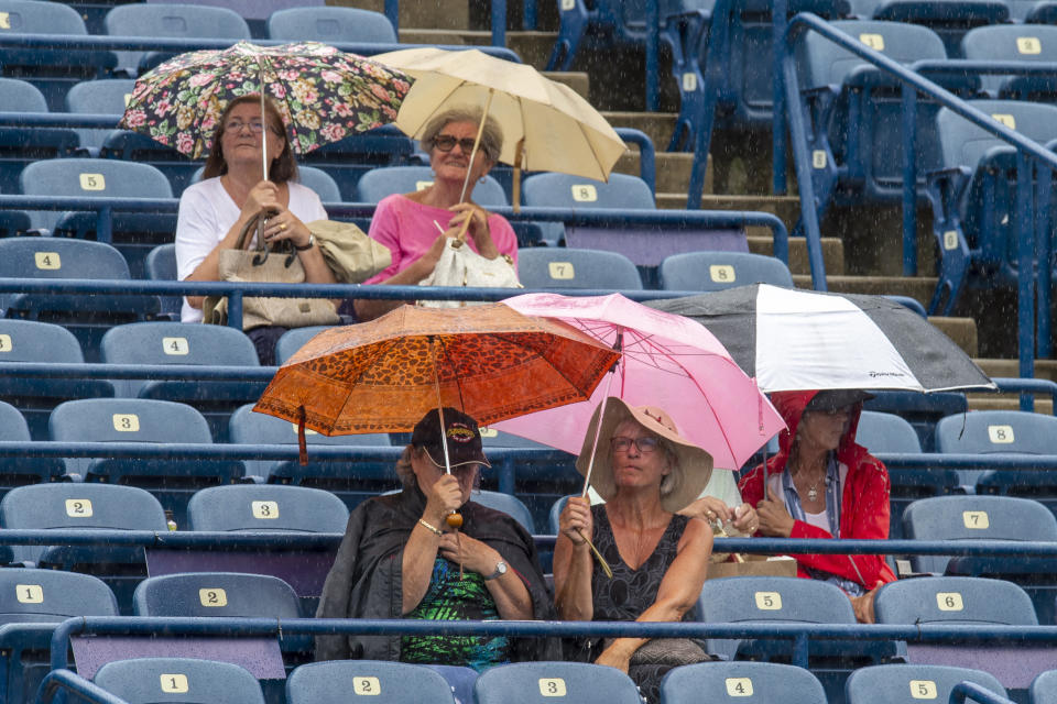 Fans take cover under umbrellas during a rain delay at the Rogers Cup tennis tournament in Toronto, Thursday, Aug. 8, 2019. (Frank Gunn/The Canadian Press via AP)