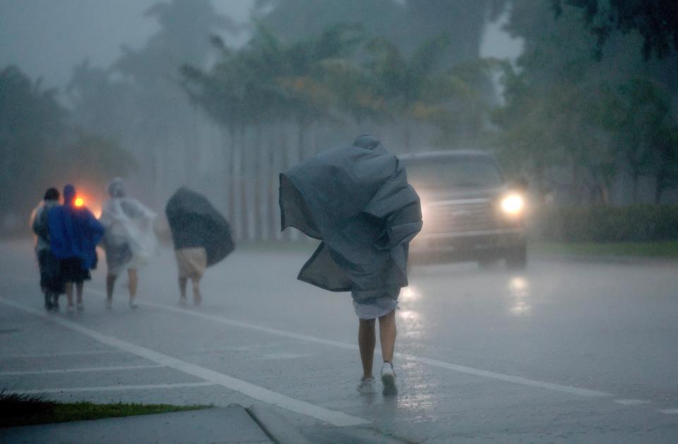 A group of people in raincoats walk east along Hollywood Blvd. in the pouring rain on Wednesday, April 12, 2023 in Hollywood, Fla. A torrential storm bought heavy showers, gusty winds and thunderstorms to South Florida on Wednesday and prompted the closure of Fort Lauderdale-Hollywood International Airport and the suspension of high-speed commuter rail service in the region. (Mike Stocker/South Florida Sun-Sentinel via AP)