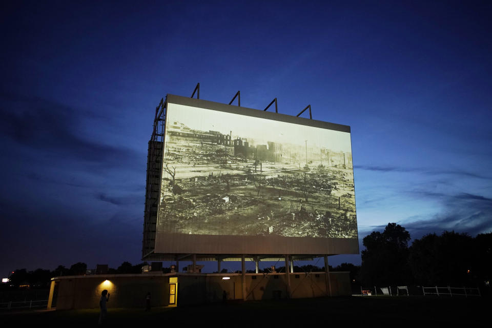 An image of devastation from the Tulsa Race Massacre is shown on a drive-in screen from a documentary called "Rebuilding Black Wall Street," during a screening of documentaries during centennial commemorations of the Tulsa Race Massacre, Wednesday, May 26, 2021, in Tulsa, Okla. (AP Photo/John Locher)