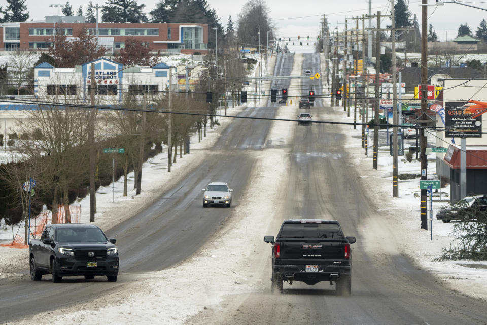 Vehicles drive on a snow cleared SE 82nd Ave. in Portland, Ore., Sunday, Jan. 14, 2024, a day after a winter storm hit the city with powerful winds, snow, sleet, and temperatures well below 20 degrees. (Mark Graves/The Oregonian via AP)