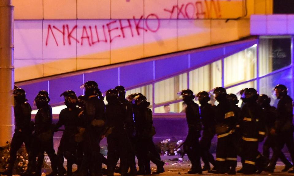 Riot police walk past a building with ‘Lukashenko go away!’ written on the wall during a protest against Lukashenko.