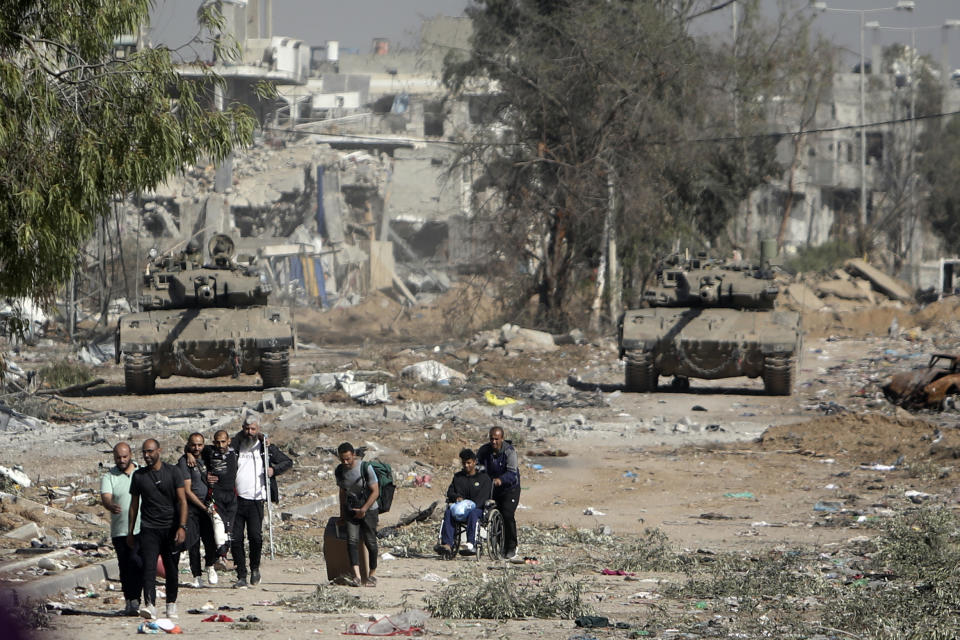 Palestinos huyen del norte de la Franja de Gaza mientras tanques israelíes bloquean la carretera de Salah al-Din, en el centro del enclave, el 24 de noviembre de 2023, durante un alto el fuego temporal. (AP Foto/Mohammed Dahman)