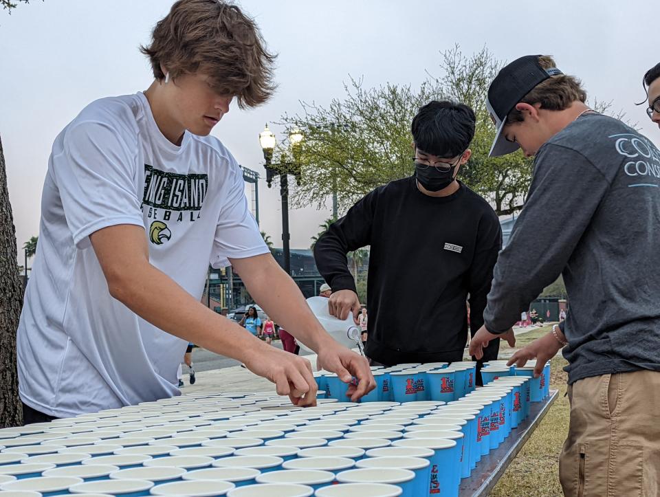 Volunteers fill cups near the starting line of the Gate River Run in Jacksonville on March 5, 2022. [Clayton Freeman/Florida Times-Union]