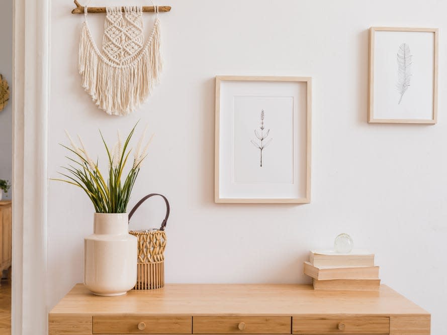 wall hanginng and frames on solid white wall with plants in vase