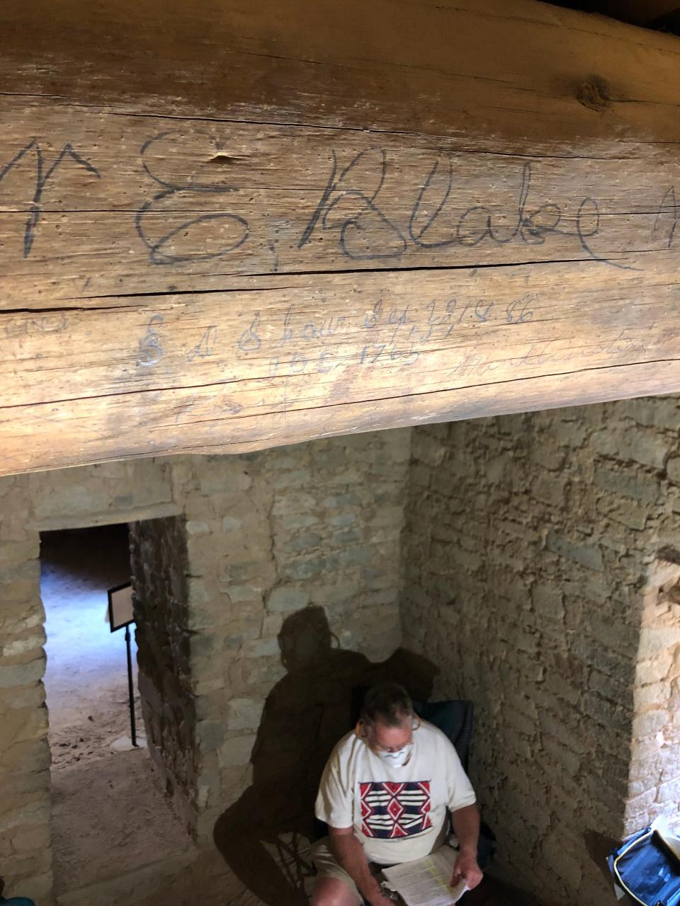 Fred Blackburn sits under a viga in a room at Aztec Ruins National Monument that was inscribed with the signatures of several early-day visitors to the site.