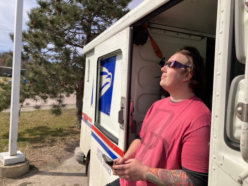 Noah Smith of Northfield, Vermont takes a break from his postal route to watch the total eclipse Monday, April 8, 2024 outside Simon's Store & Deli in St. George, Vermont.