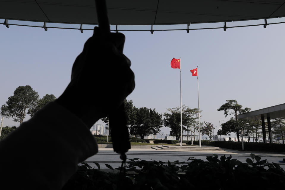 A pro-Beijing demonstrator raises a placard in front of the Chinese National flag and the Hong Kong flag during a protest outside Legislative building in Hong Kong, Wednesday, Jan. 23, 2019. Hong Kong’s legislature has taken up for consideration a bill that punishes anyone who "publicly and intentionally insults" the Chinese national anthem with up to three years in prison. (AP Photo/Vincent Yu)