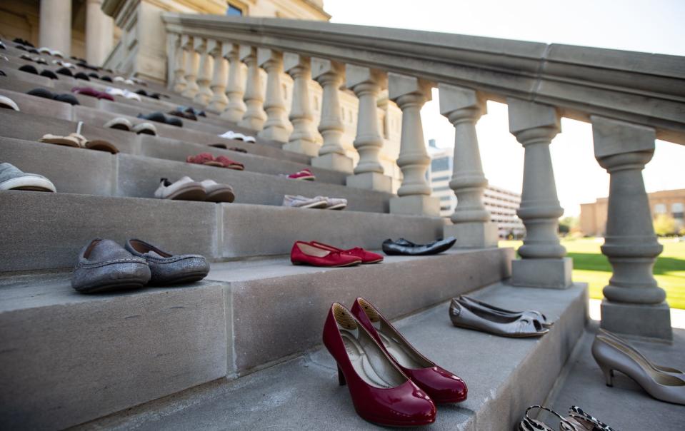 Seventy pairs of shoes were placed on the west Capitol steps during a domestic violence vigil on Thursday, Sept. 14, 2023, to represent the women and children killed each year by abusers with firearms in Michigan.