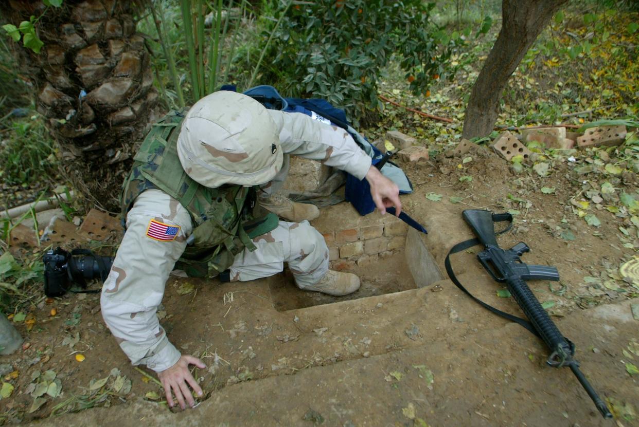 A US soldier from the 1st Brigade of 4th Infantry Division on Dec. 15, 2003 gets ready to enter the hole where toppled dictator Saddam Hussein was captured in Ad Dawr. Two days earlier, Hussein was captured there in the hole under a small hut, near his hometown of Tikrit, 110 miles north of Baghdad.