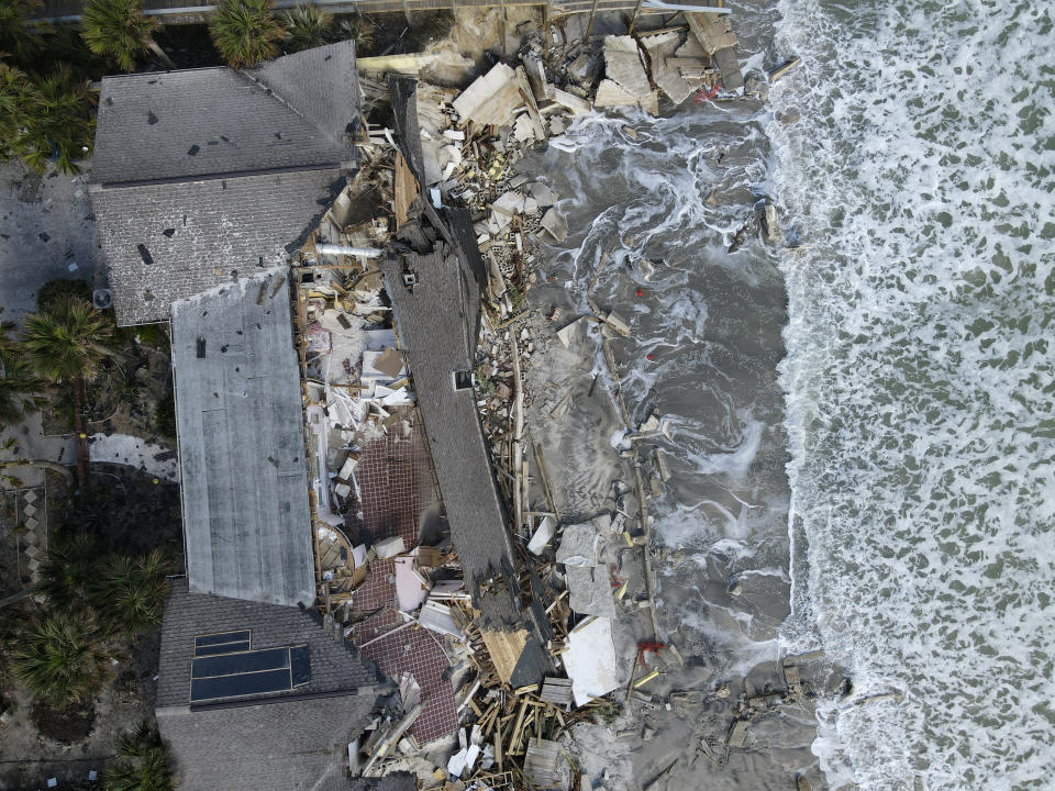 Waves lap the eroded beach below a home that half collapsed after the sand supporting it was swept away, following the passage of Hurricane Nicole, Saturday, Nov. 12, 2022, in Wilbur-By-The-Sea, Fla. (AP Photo/Rebecca Blackwell)