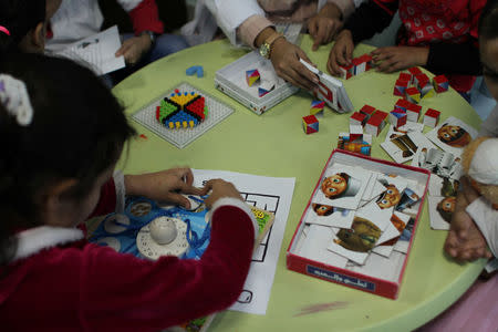 Young girls, severely burnt and maimed by explosions in Yemen, Syria and Iraq, play puzzles as an occupational therapist assesses their cognitive development inside a Medecins Sans Frontieres hospital in Amman, Jordan, November 20, 2016. Lin Taylor/Thomson Reuters Foundation via REUTERS