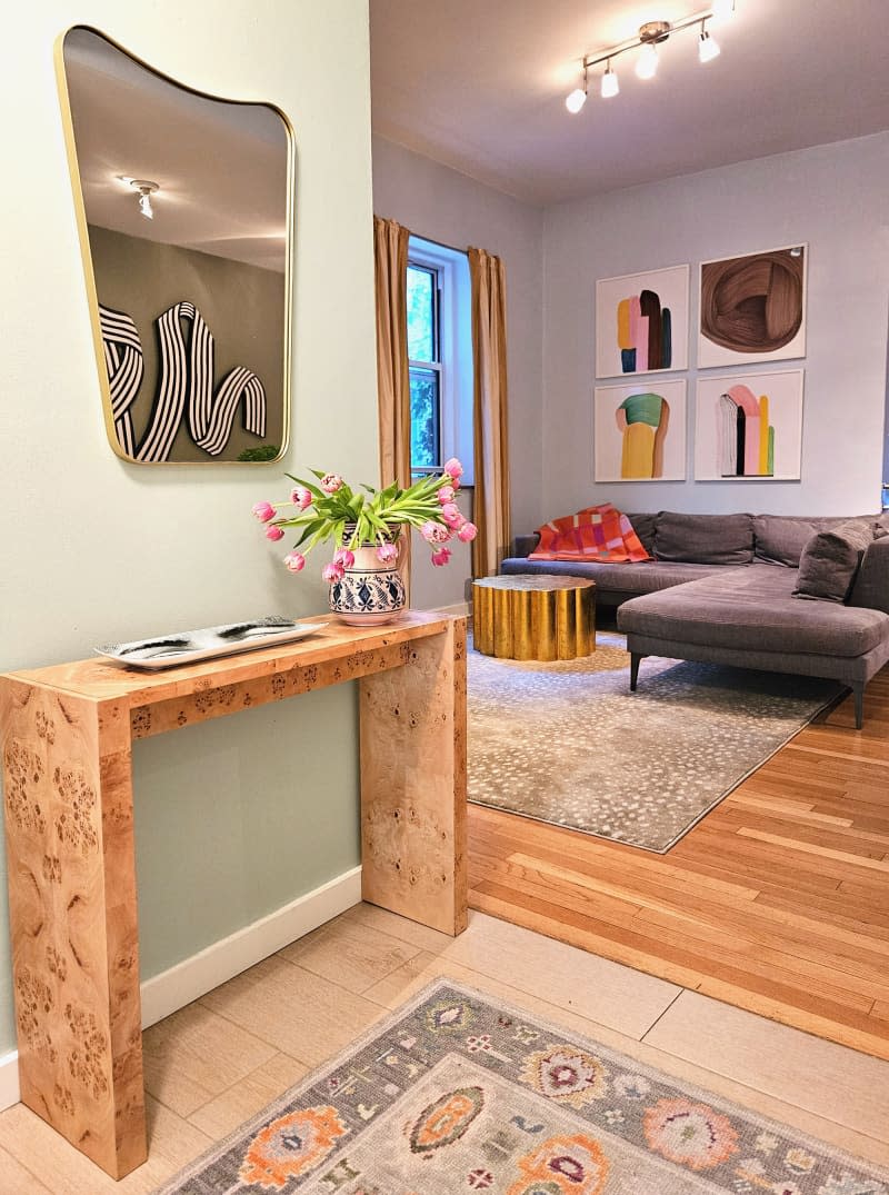 entryway with console table and curved mirror with view into living room