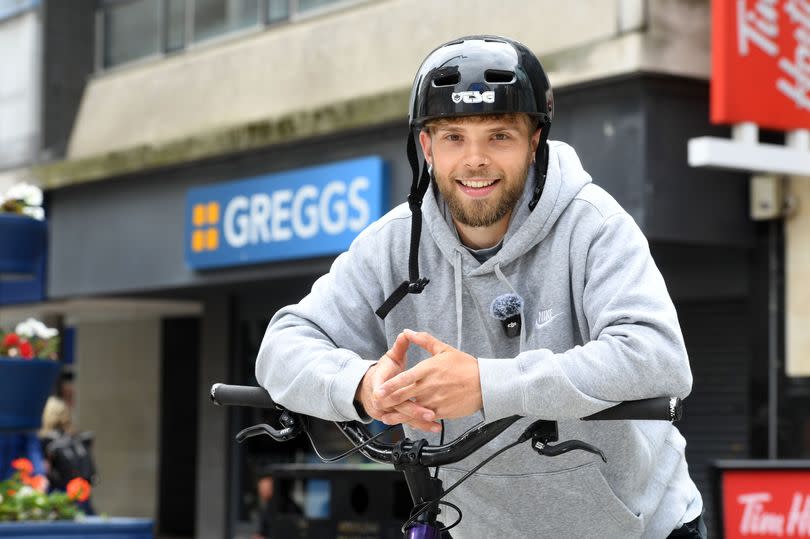 Man in cycle helmet and with bike at Greggs