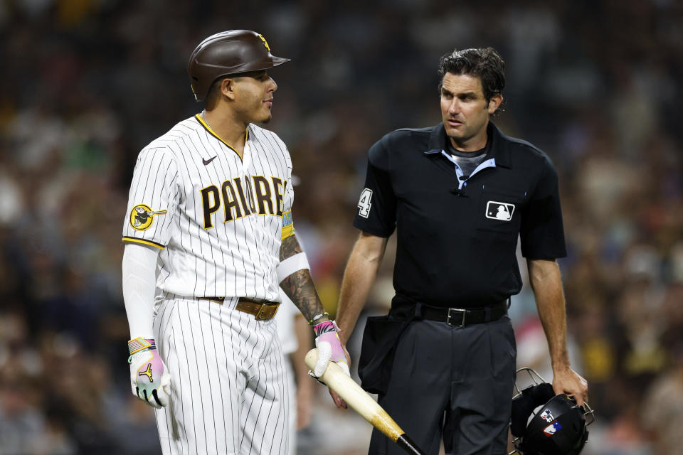 San Diego Padres' Manny Machado, left, is escorted to first base by umpire John Tumpane after Machado was hit by a pitch from Pittsburgh Pirates' Angel Perdomo during the seventh inning of a baseball game Tuesday, July 25, 2023, in San Diego. (AP Photo/Derrick Tuskan)