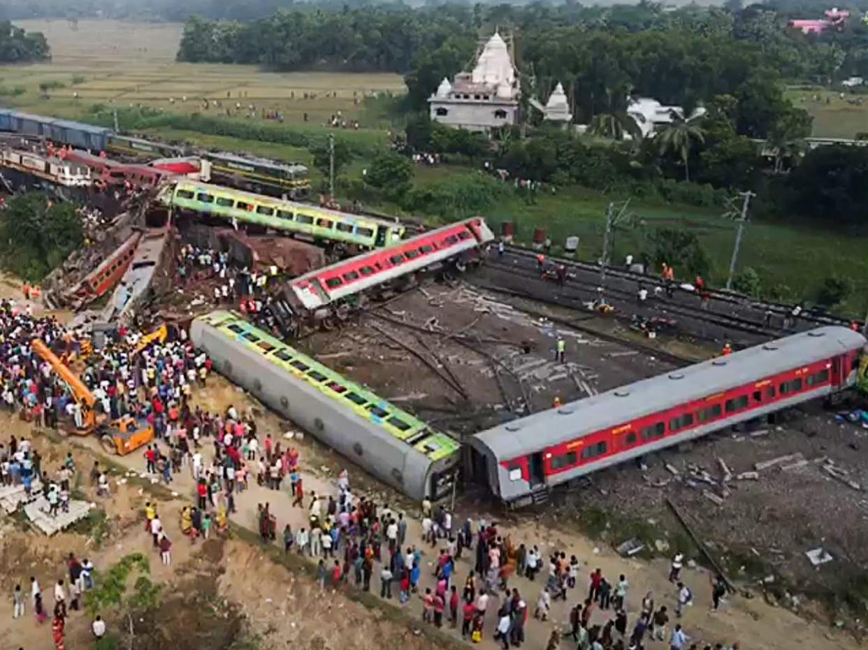 This screen grab made from AFPTV video footage taken on June 3, 2023 shows people gathering at the accident site of a three-train collision near Balasore, in the eastern state of Odisha.