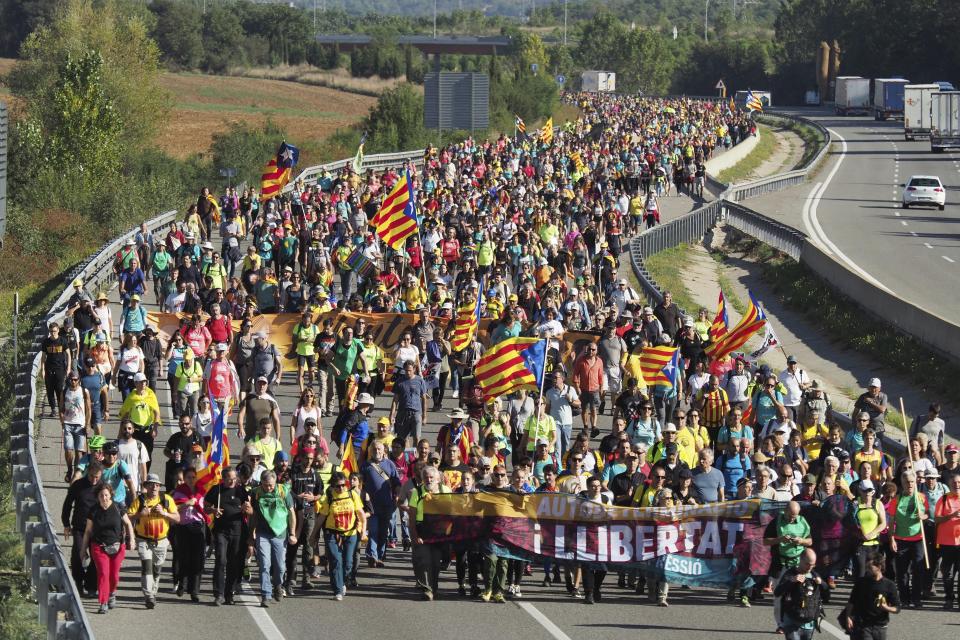 Demonstrators walk along a highway in Girona, Spain, Wednesday, Oct. 16, 2019. Thousands of people have joined five large protest marches across Catalonia that are set to converge on Barcelona, as the restive region reels from two straight days of violent clashes between police and protesters. The marches set off from several Catalan towns and aimed to reach the Catalan capital by Friday. (AP Photo/Mar Grau)