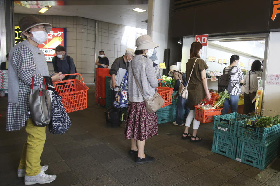 People wearing face masks to protect against the spread of the new coronavirus keep social distancing as they wait to enter a fruit and vegetable shop in Yokohama, near Tokyo, Tuesday May 12, 2020. (AP Photo/Koji Sasahara)