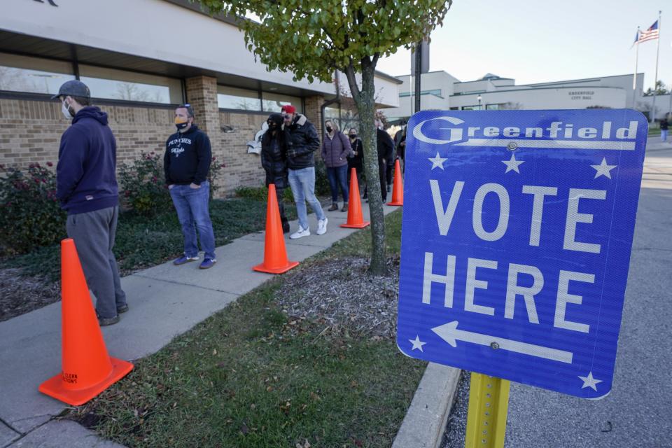 FILE- In this Nov. 3, 2020, file photo people line up to vote outside the Greenfield Community Center on Election Day in Greenfield, Wis. The Wisconsin Supreme Court sided with Democrats on Friday, April 9, 2020, and ruled that the state elections commission should not remove from the rolls voters flagged as possibly having moved, something conservatives have wanted done for nearly two years. (AP Photo/Morry Gash)