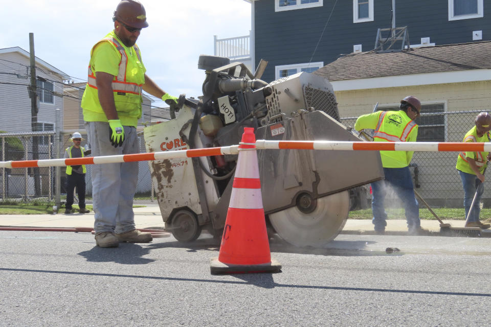 A worker uses an industrial cutting machine to open a section of the street in Ocean City, N.J. on Sept. 12, 2023, at the start of land-based probing along the right-of-way where a power cable for New Jersey's first offshore wind farm is proposed to run. Several protestors were arrested trying to block the work for the project being done by Danish wind energy company Orsted. (AP Photo/Wayne Parry)