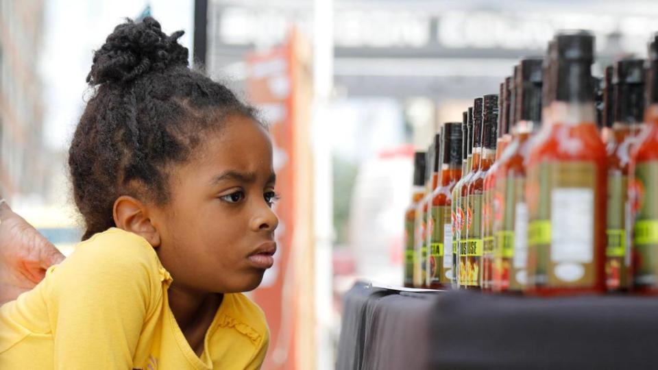 Camilla-Maria Paul, 5, examines a row of hot sauce on Saturday, June 24, 2023 at Fifth Third Pavilion in Lexington, Ky. Many farmers sell processed items such hot sauce and salsa, as well as canned goods.