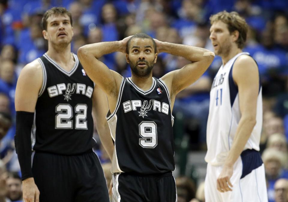 San Antonio Spurs' Tony Parker (9), of France, reacts after being charged with a foul as teammate Tiago Splitter (22), of Brazil, and Dallas Mavericks' Dirk Nowitzki, right, of Germany, look on late in the second half of Game 6 of an NBA basketball first-round playoff series on Friday, May 2, 2014, in Dallas. The Mavericks won 113-111. (AP Photo/Tony Gutierrez)