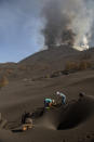 People clean up the ash off a house from the volcano in Las Manchas on the Canary island of La Palma, Spain on Thursday Oct. 14, 2021. Hundreds of people in Spain's Canary Islands are fearing for their homes and property after a new lava stream from an erupting volcano threatened to engulf another neighborhood on the island of La Palma. (AP Photo/Saul Santos)