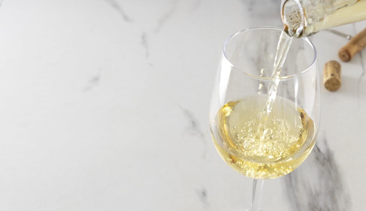 Two wine glasses full of white wine on the marble table.Pouring sweet white wine.Empty space