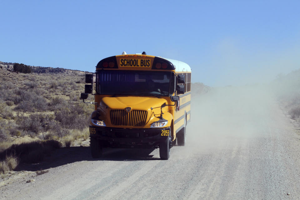 A school bus driven by Kelly Maestas travels along a dirt road outside Cuba, N.M., Oct. 19, 2020. The switch to remote learning in rural New Mexico has left some students profoundly isolated — cut off from others and the grid by sheer distance. The school system is sending school buses to students' far-flung homes to bring them assignments, meals and a little human contact. (AP Photo/Cedar Attanasio)